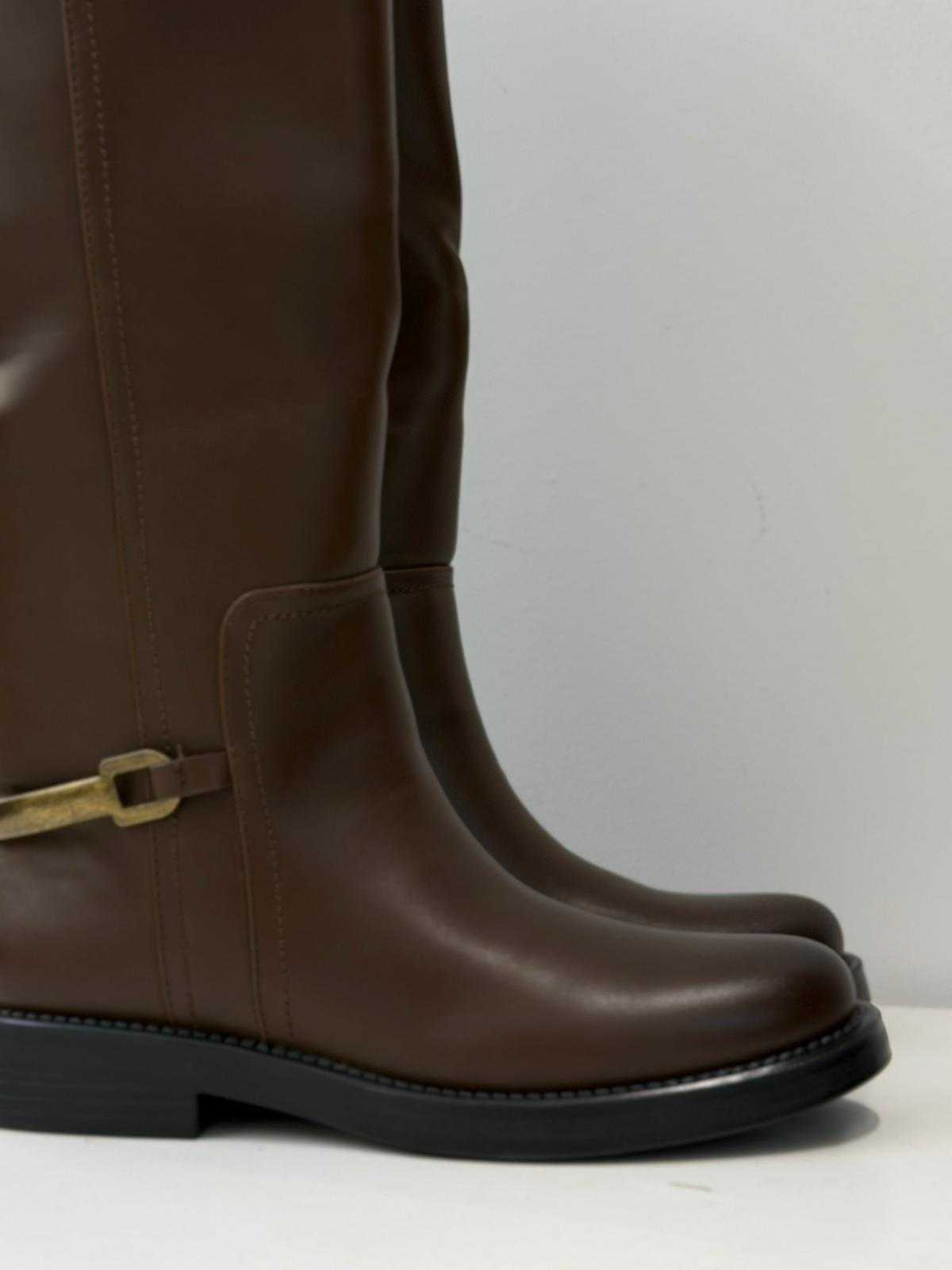 Women’s brown knee-high flat boots with metal strap detail and smooth finish