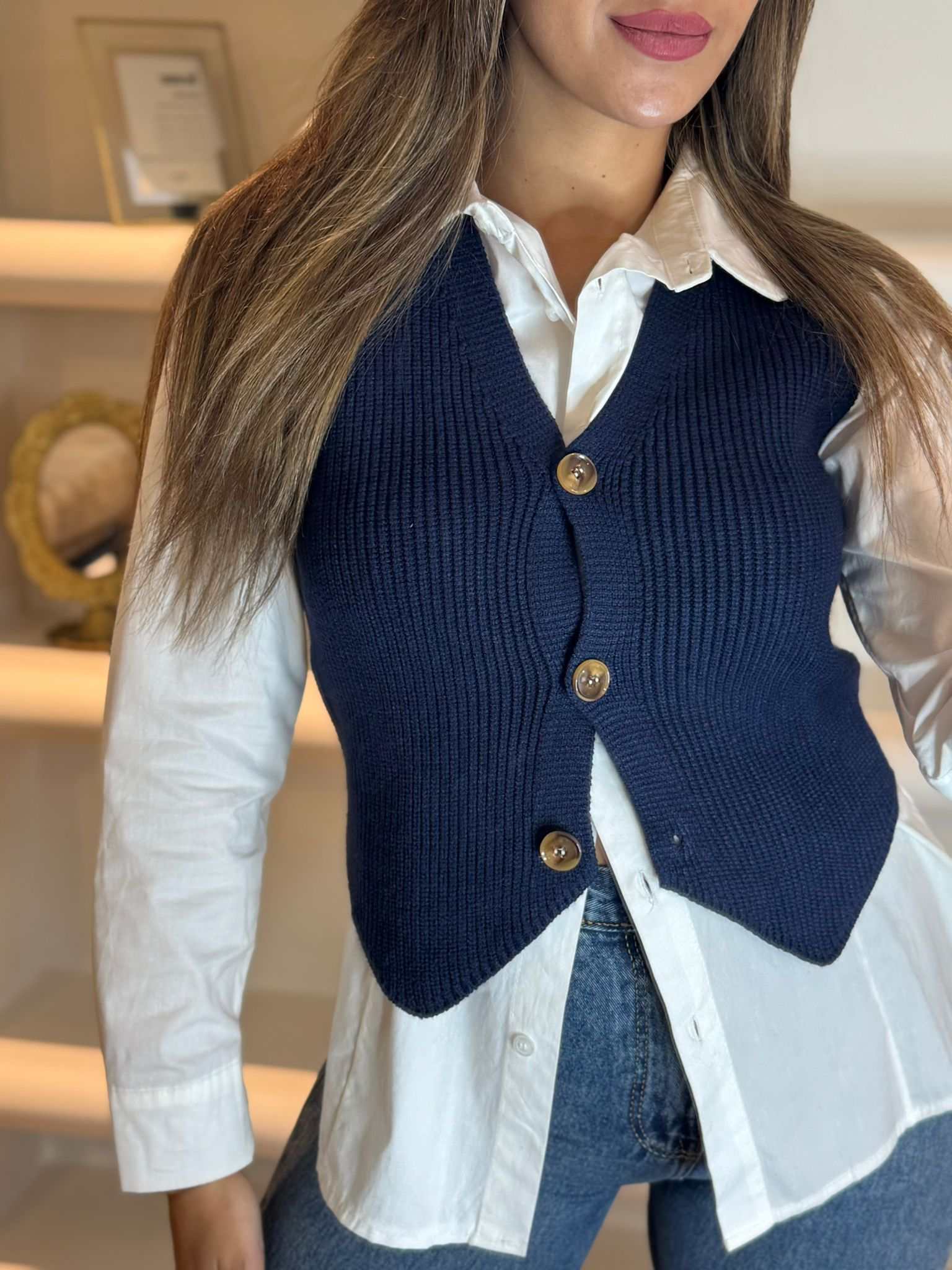 Women’s navy knit button-front vest layered over a white shirt